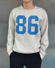 Sand colored pullover with blue text that says "86"