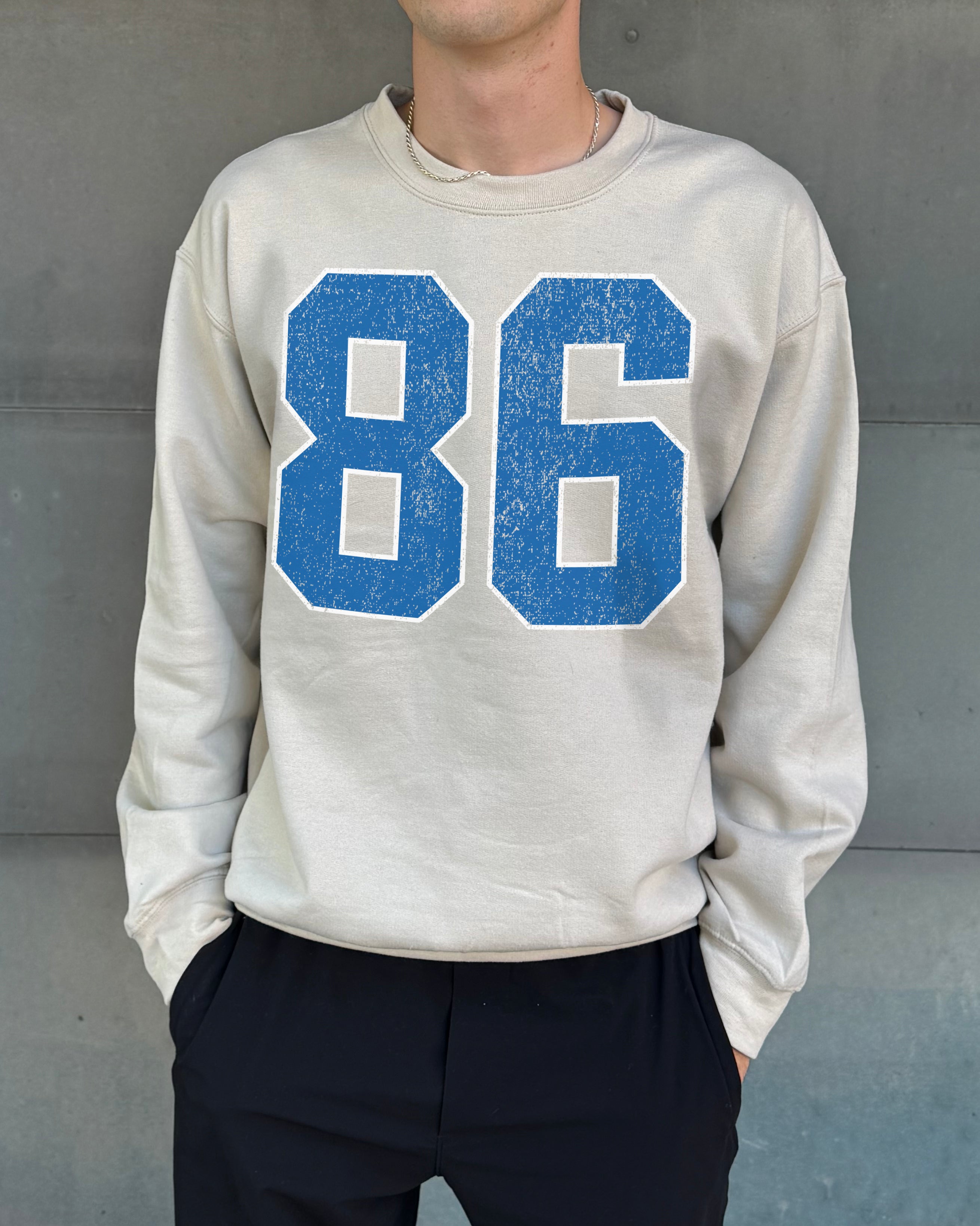 Sand colored pullover with blue text that says "86"