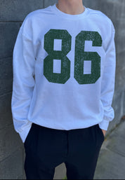 White colored pullover with green text that says "86"