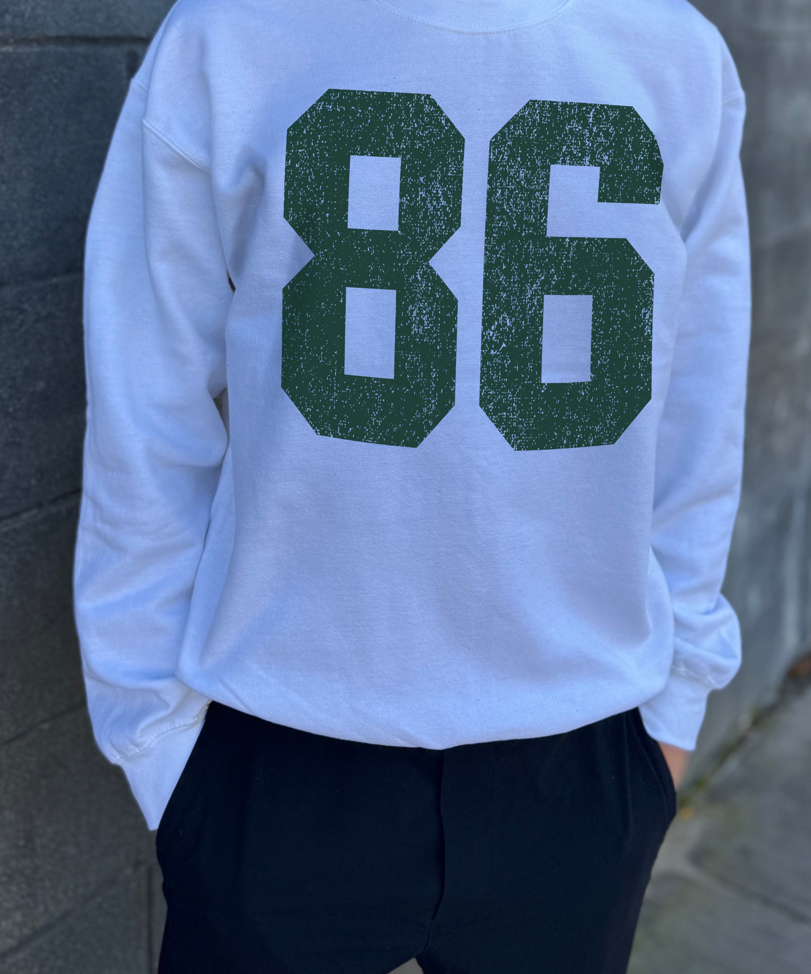 White colored pullover with green text that says "86"