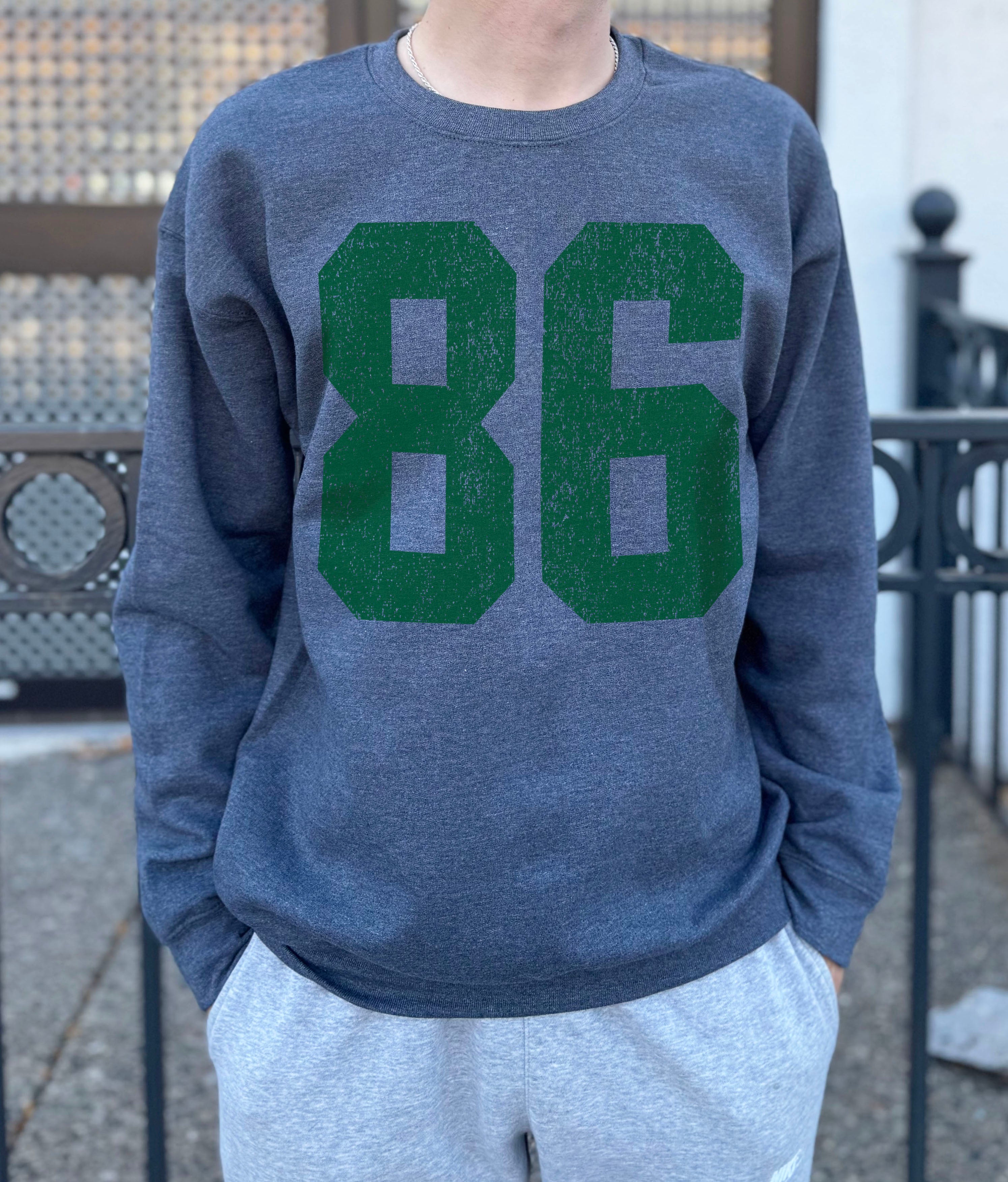 grey colored pullover with green text that says "86"