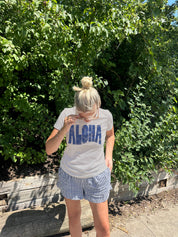 White Tee shirt that says "aloha" in dark blue on a woman 