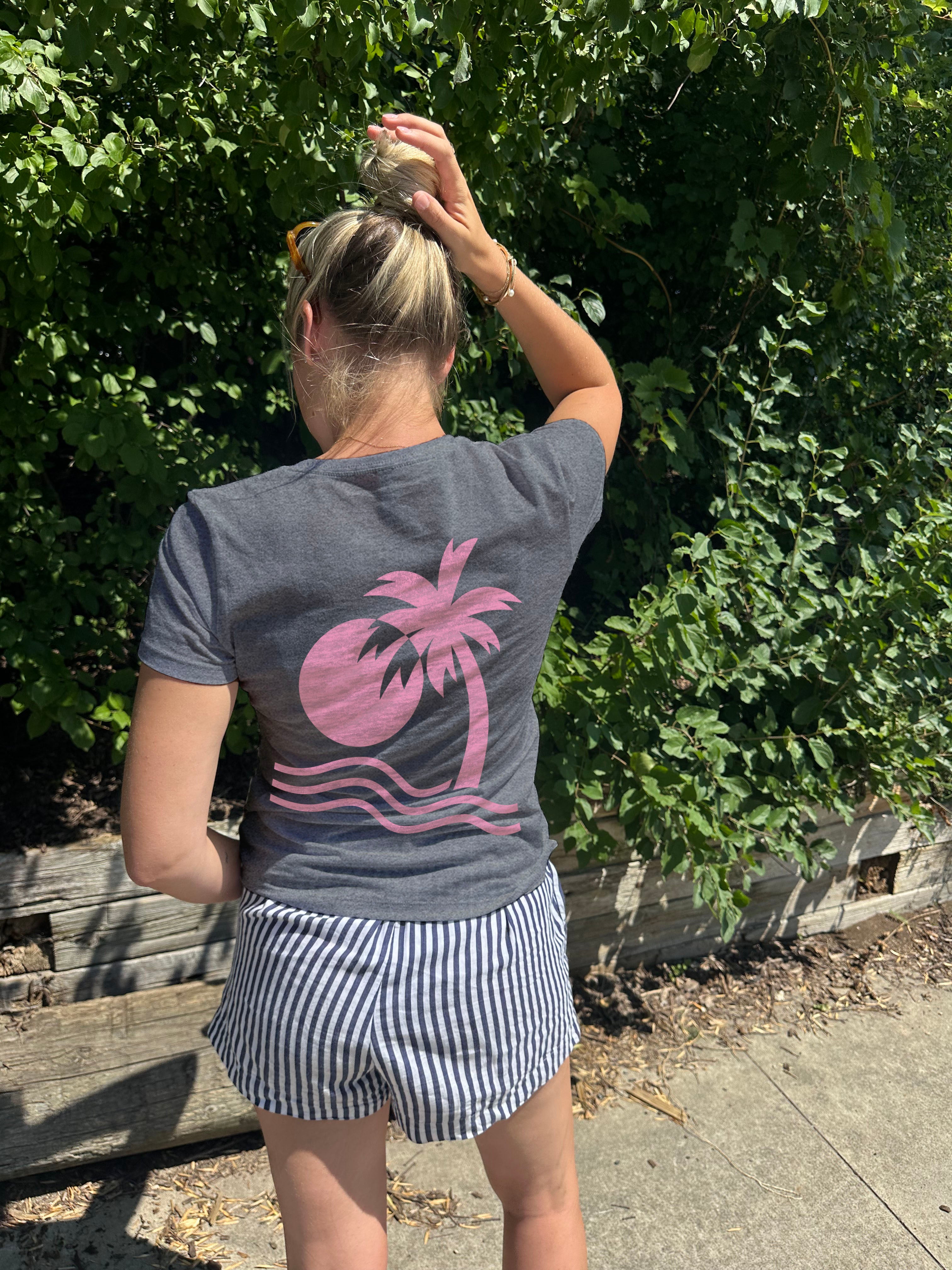 Grey Tee shirt that has a palm tree in pink from the back