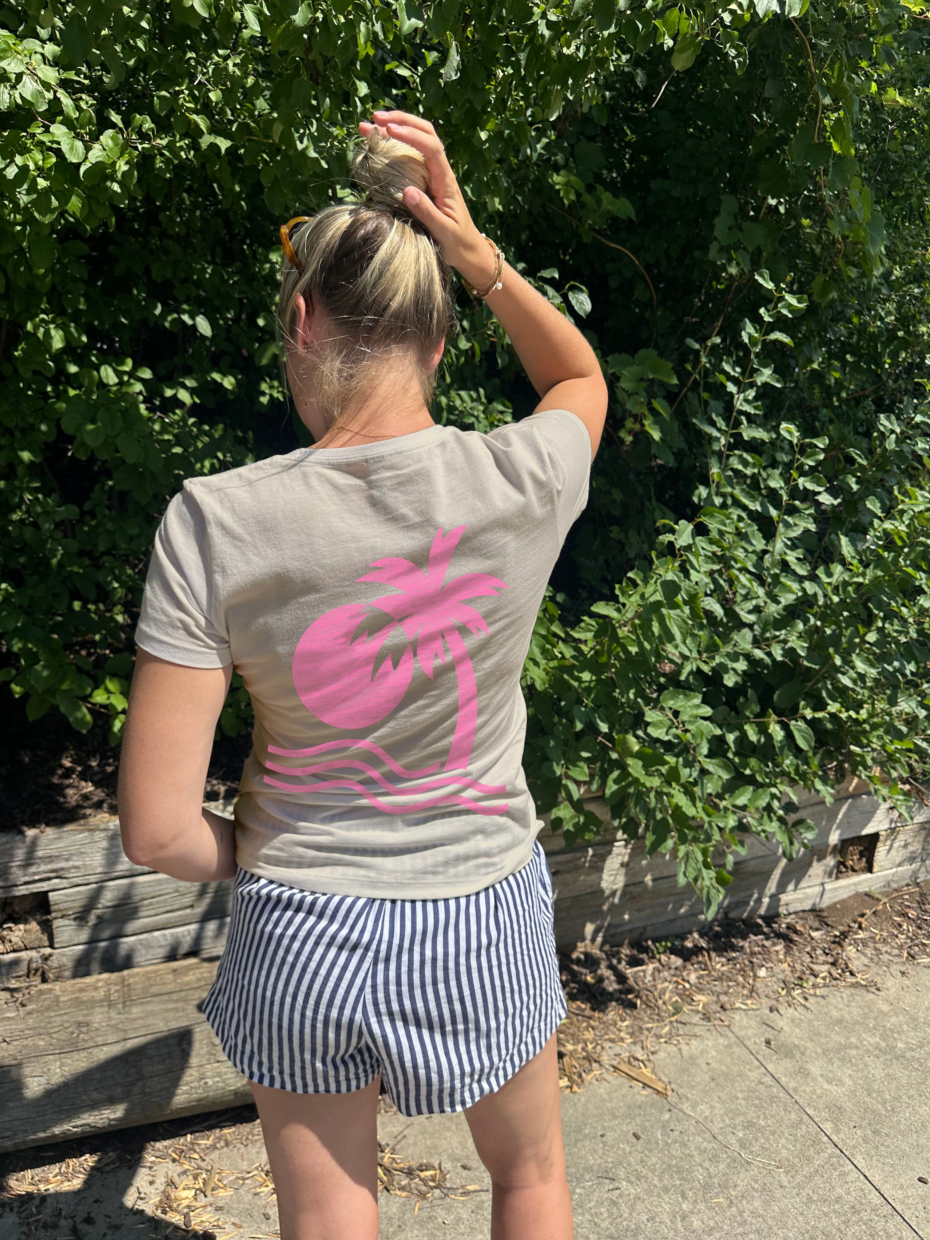 light green Tee shirt that has a pink palm tree graphic on a woman from behind
