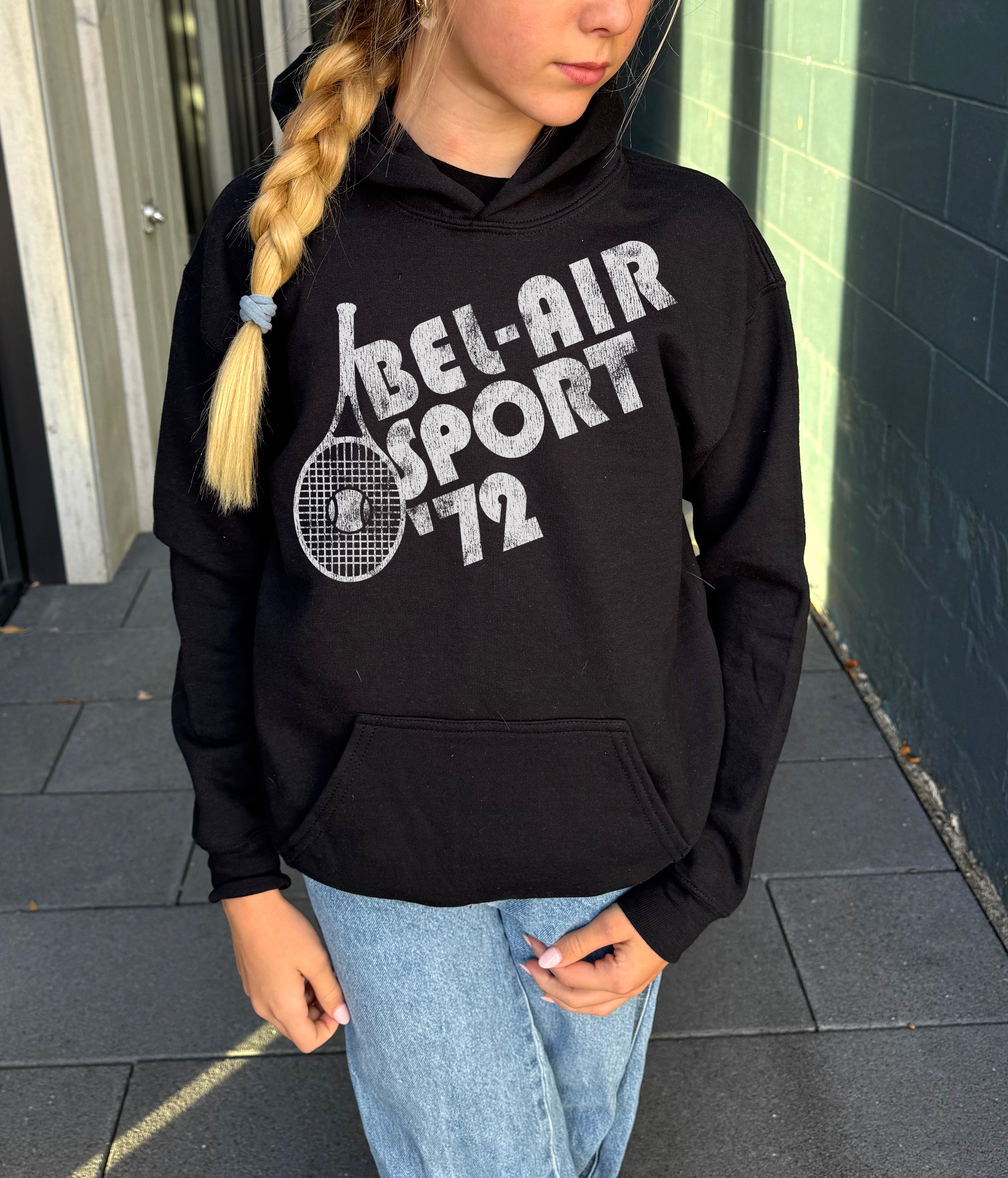 Girl in black hoodie that says "Bel-Air Sport 72" in white text