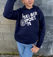Girl in dark blue hoodie that says "Bel-Air Sport 72" in white text