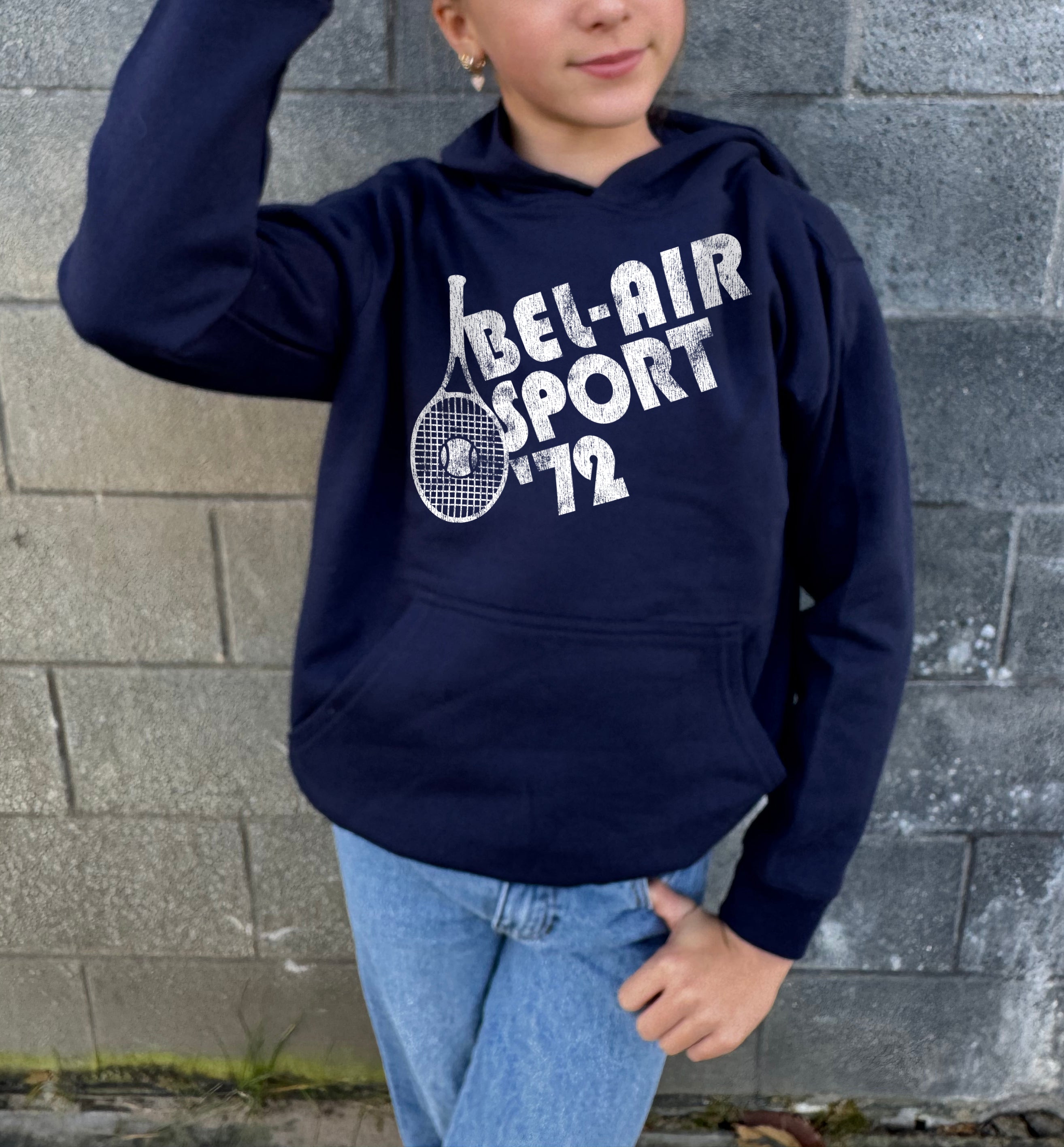 Girl in dark blue hoodie that says "Bel-Air Sport 72" in white text