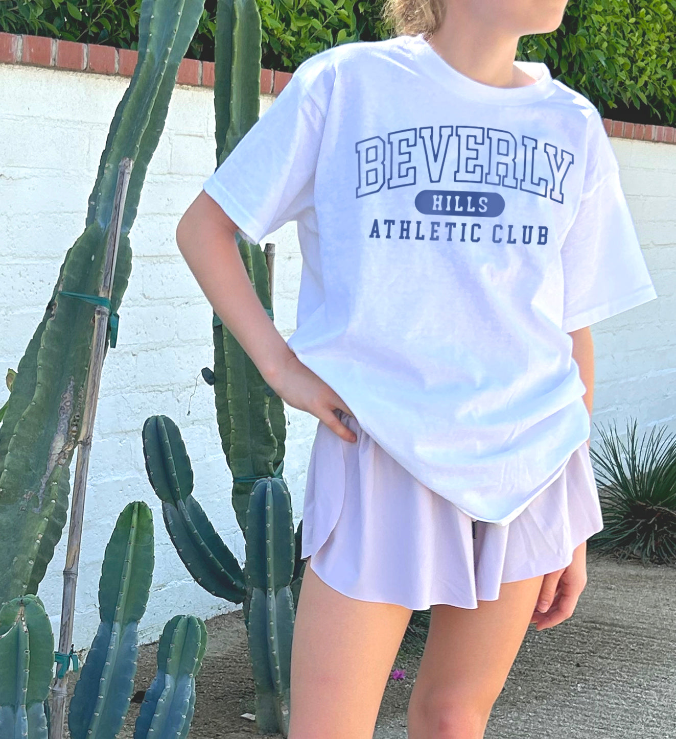Girl in white shirt that says "Beverly Hills" in blue text