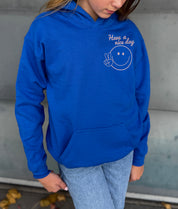 Girl in blue hoodie that says "have a nice day" in pink text with Smiley face