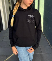 Girl in black hoodie that says "have a nice day" in white text with Smiley face