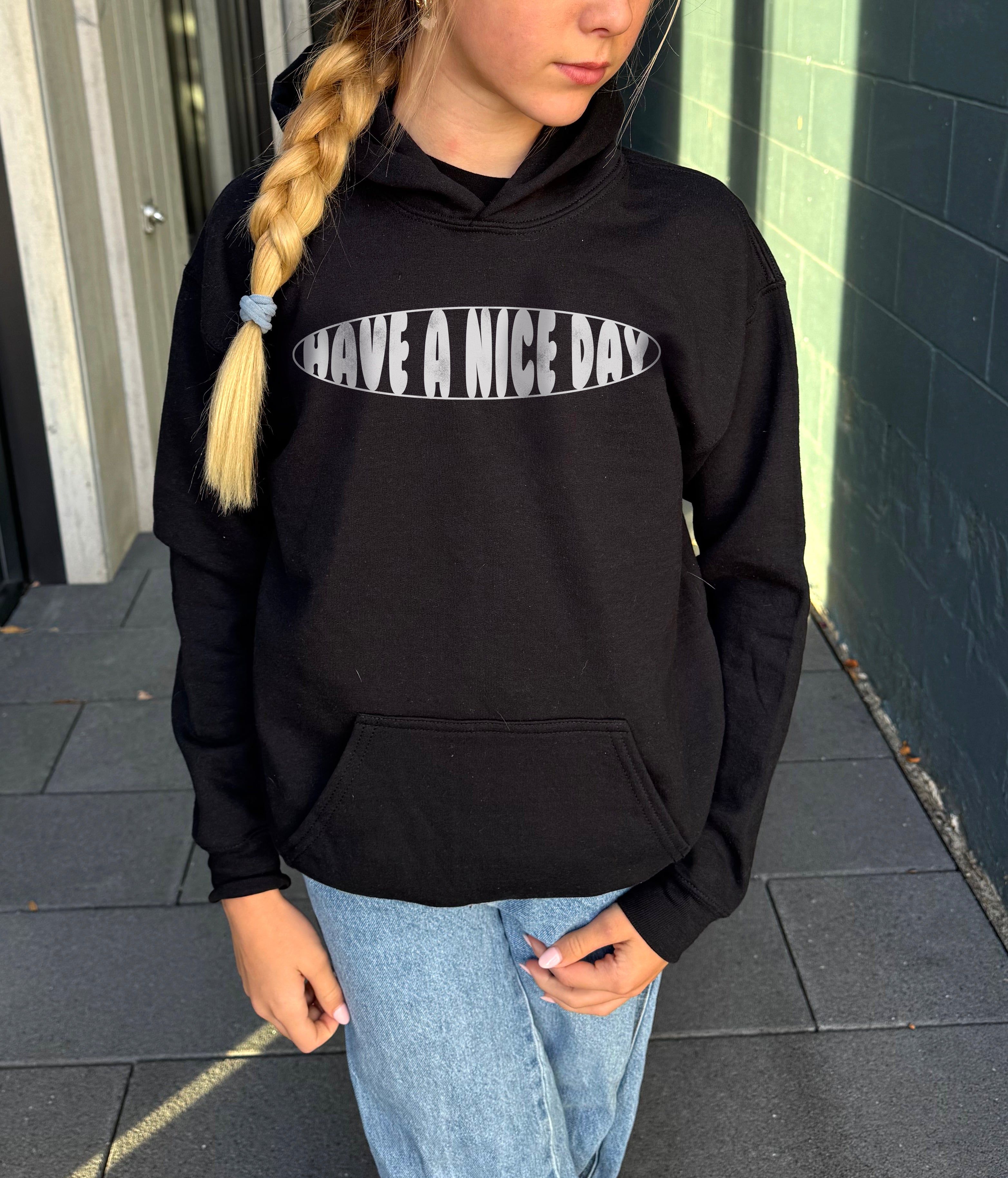 Girl in black hoodie that says "have a nice day" in white text 