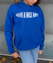 Girl in blue hoodie that says "Have a nice day" in white text 