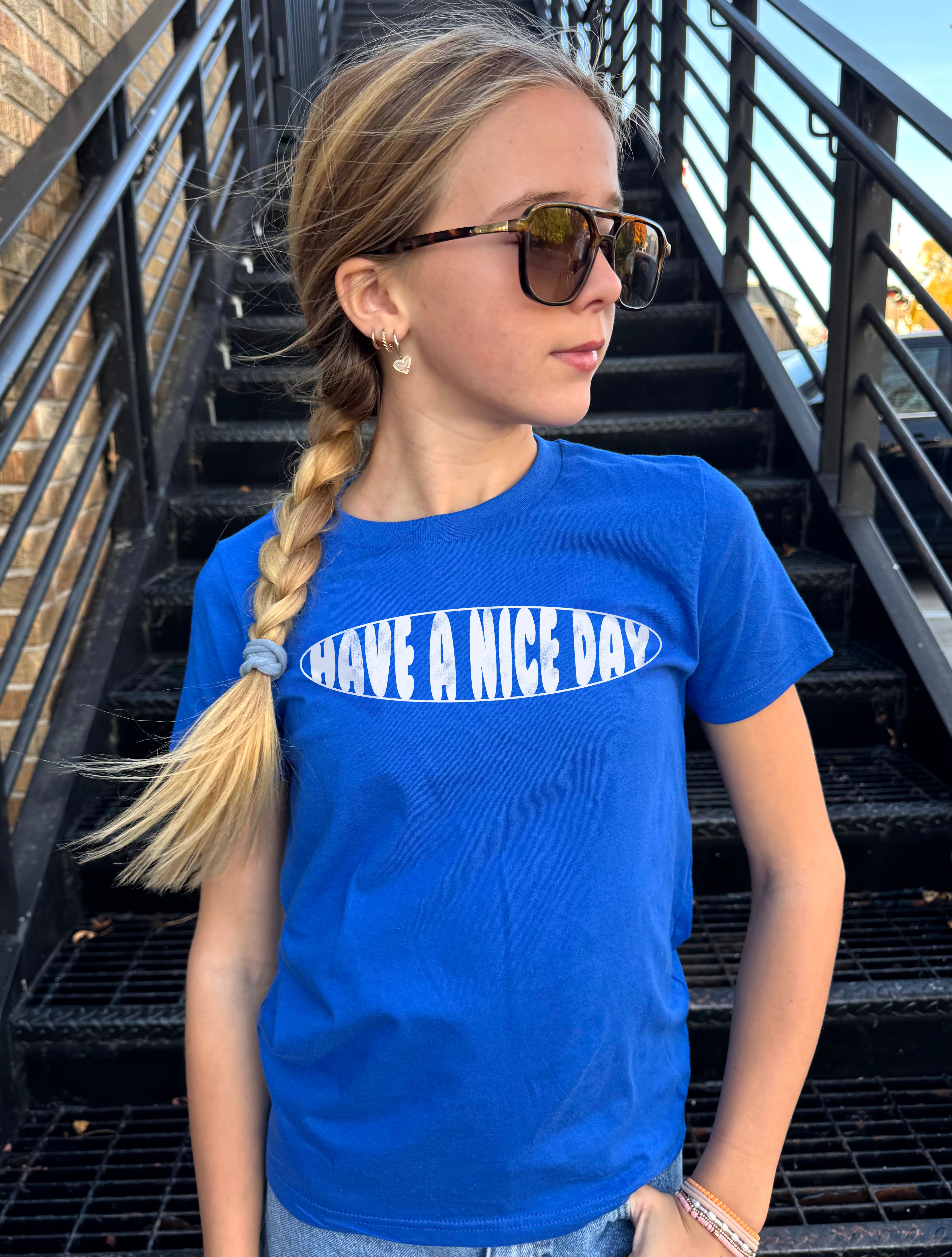Girl in blue shirt that says "Have a nie day" in white text