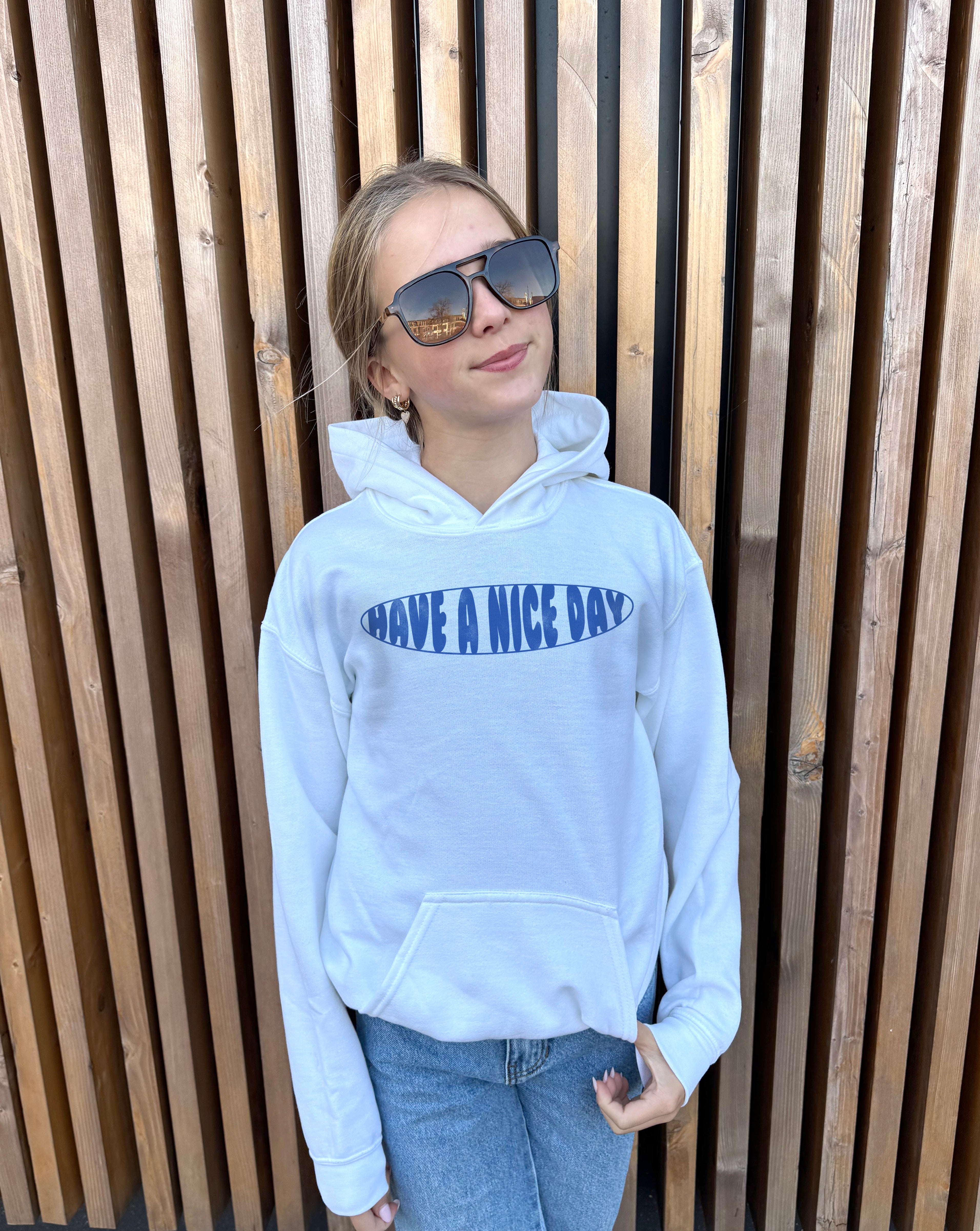 Girl in blue hoodie that says "Have a  nice Day" in white text 