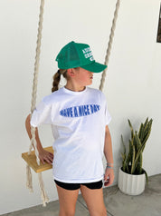 Girl in white shirt that says "Have a nie day" in blue text