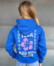 Girl in blue hoodie that says "Toes to the nose" in white text with Hawaiian flower