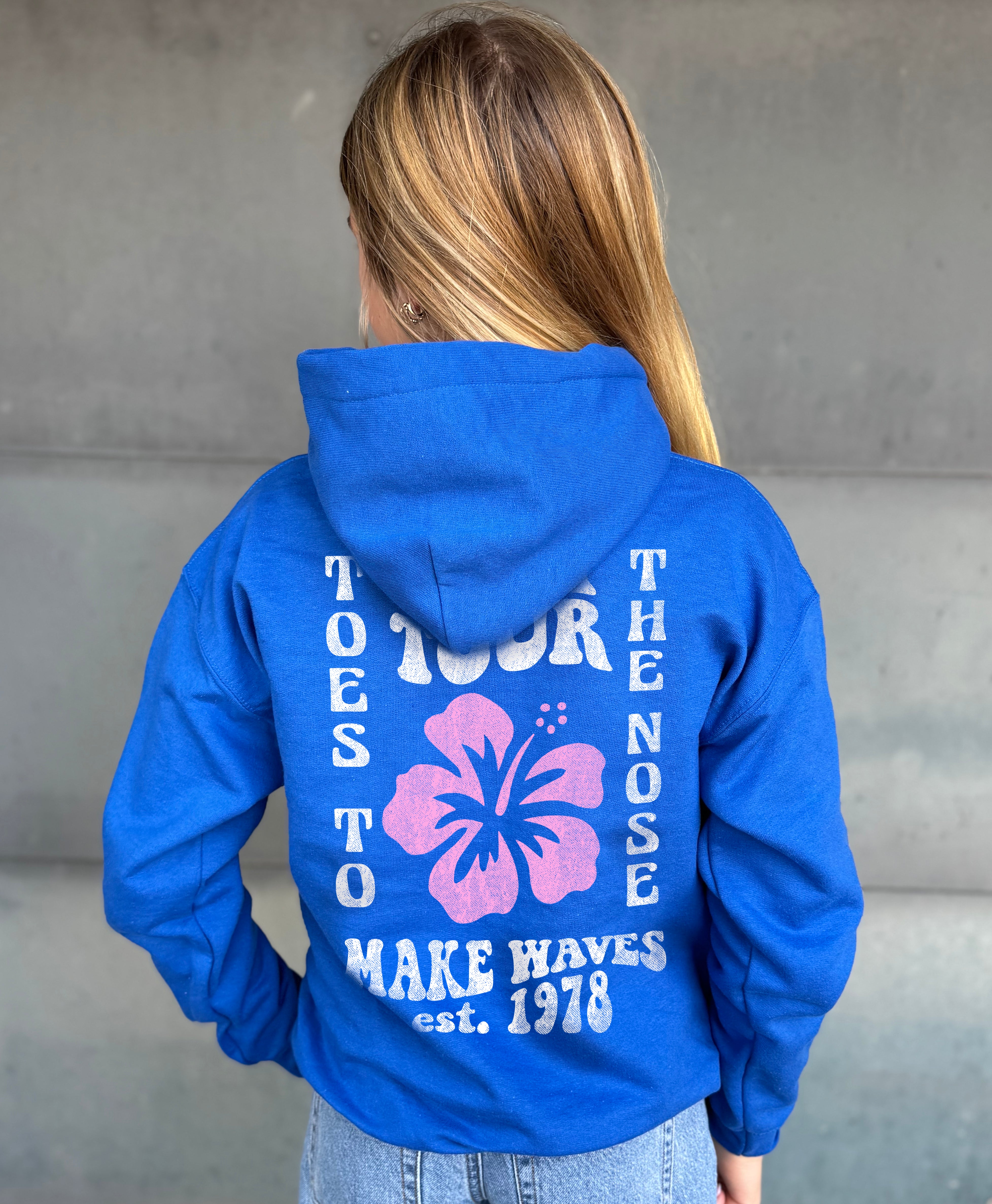 Girl in blue hoodie that says "Toes to the nose" in white text with Hawaiian flower