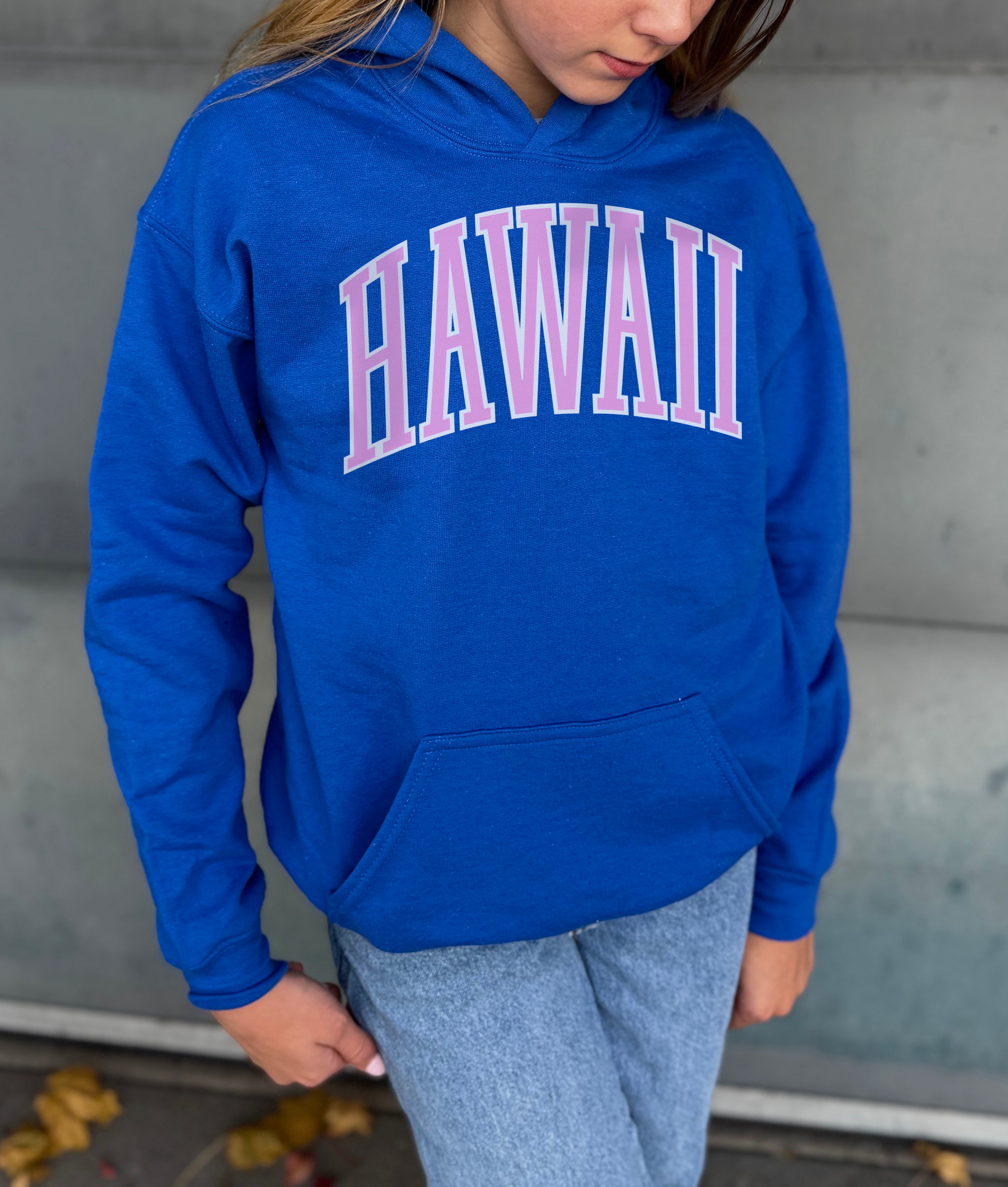 Girl in blue hoodie that says "Hawaii" in pink text
