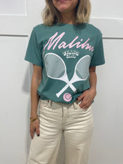 Woman in seafoam pullover that has pink text that says "Malibu"