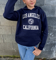 Girl in blue hoodie that says "Los Angeles, California" in white text 