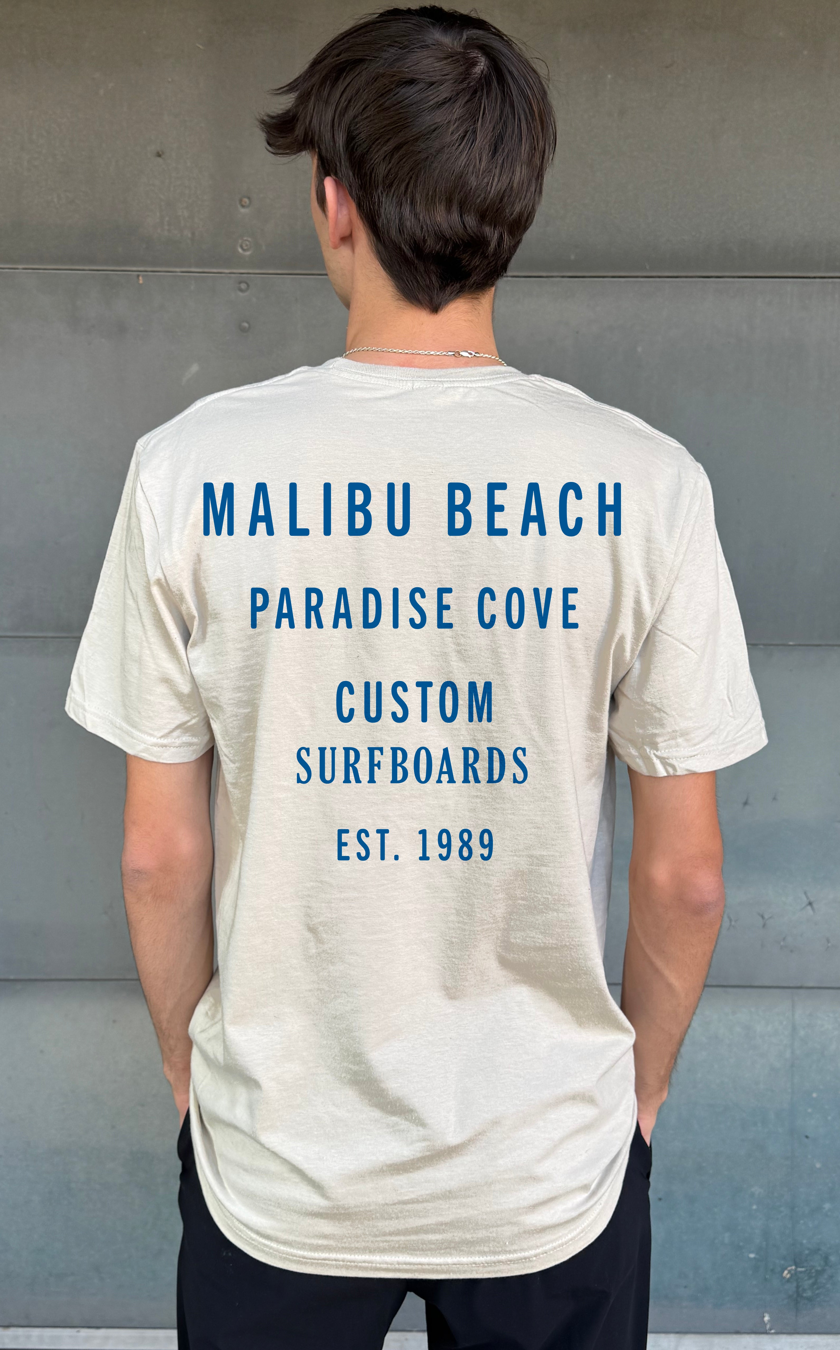 Boys t-shirt from the back in light yellow with blue text that says "Malibu Beach Paradise Cove Custom Surfboards" 