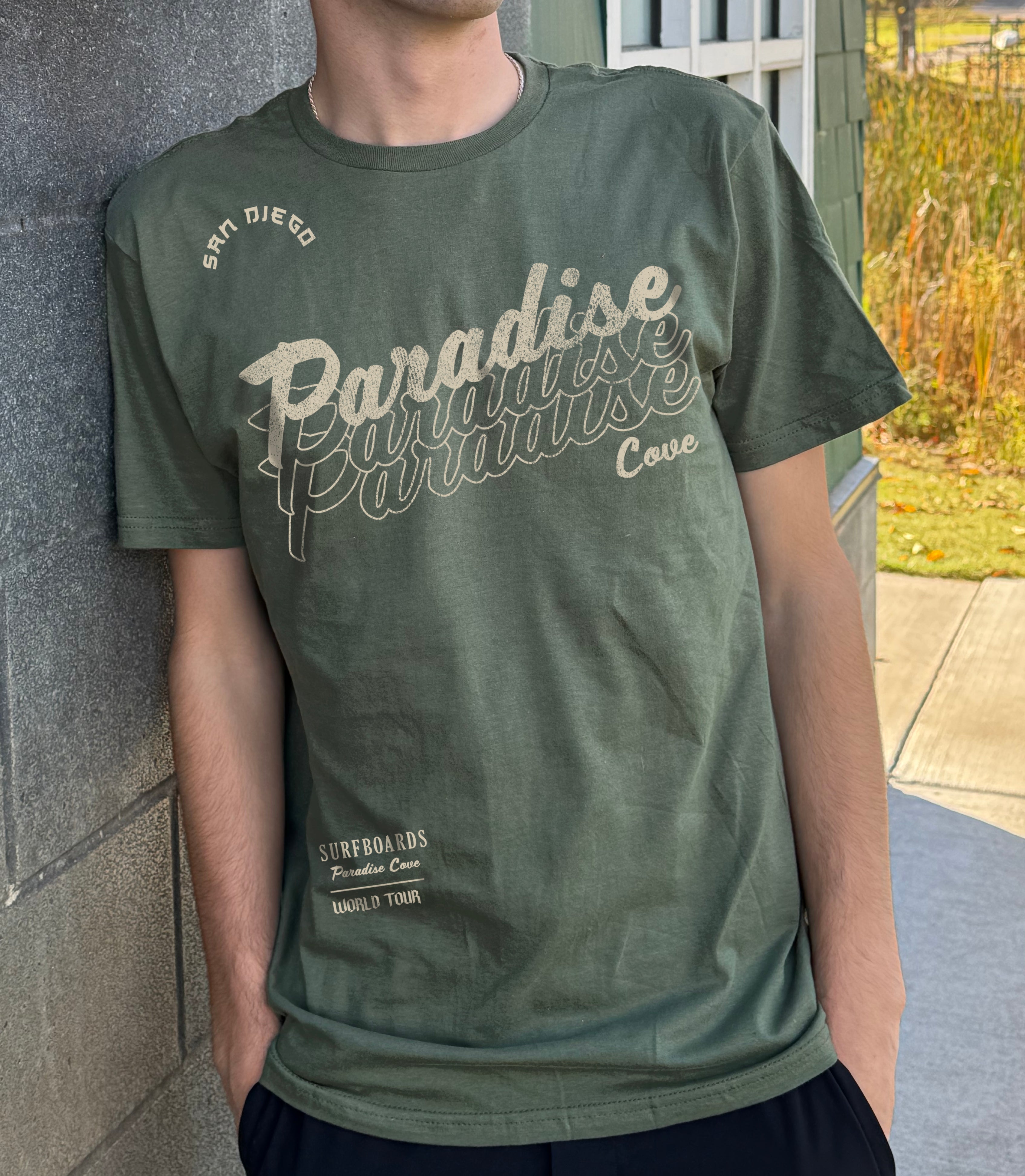 Boys shirt in army green that says "Paradise Cove" in ight yellow lettering