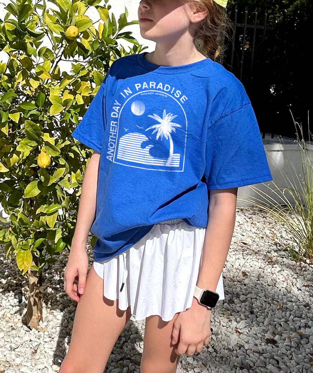 Girl in blue shirt that says "Another Day in Paradise" in white text