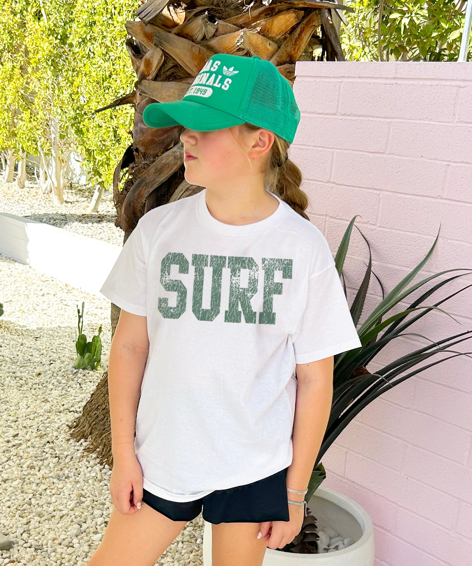 Girl in white tee shirt with green lettering that say "Surf"