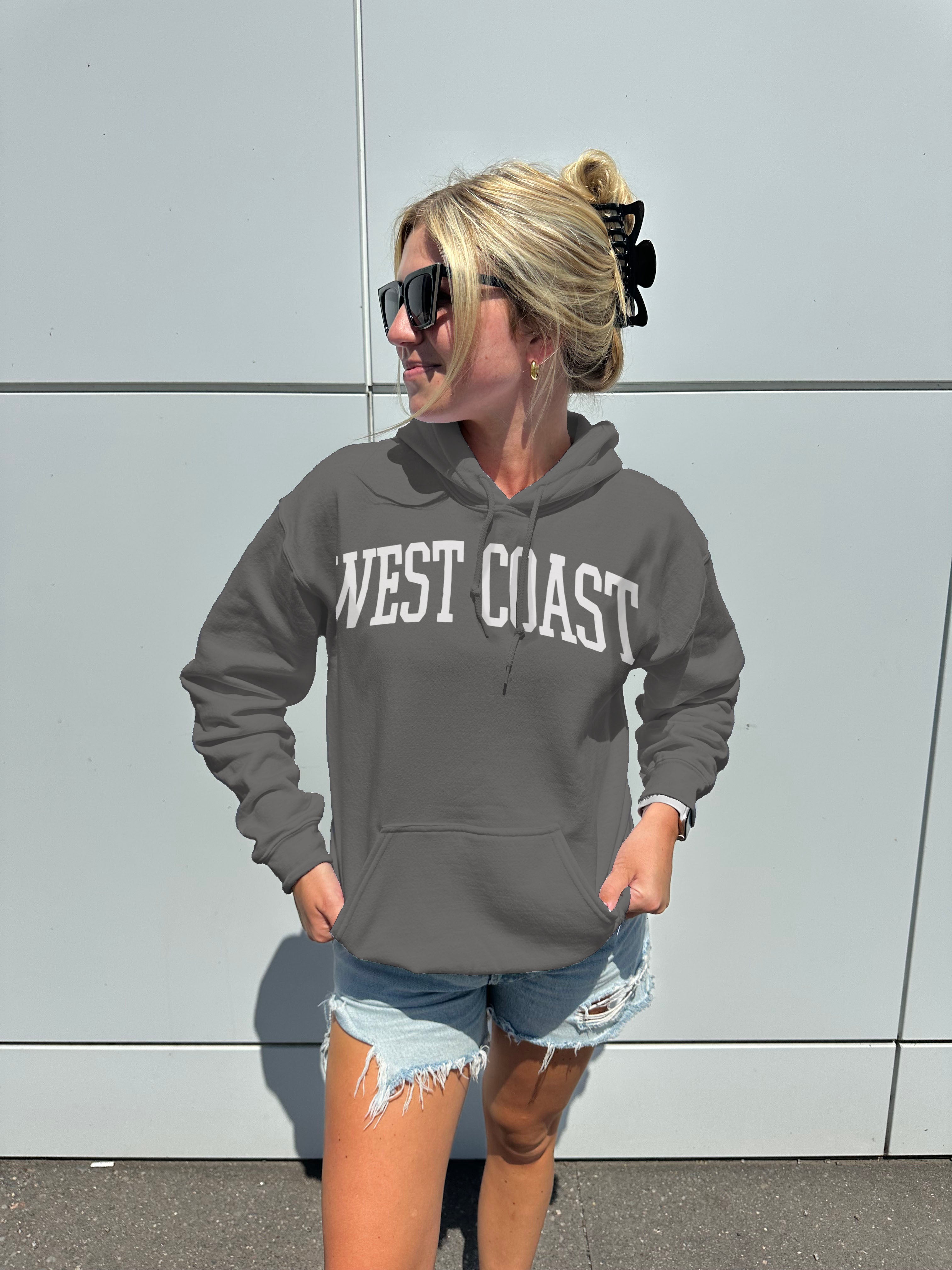 woman in gray hoodie that says " West Coast" in white text