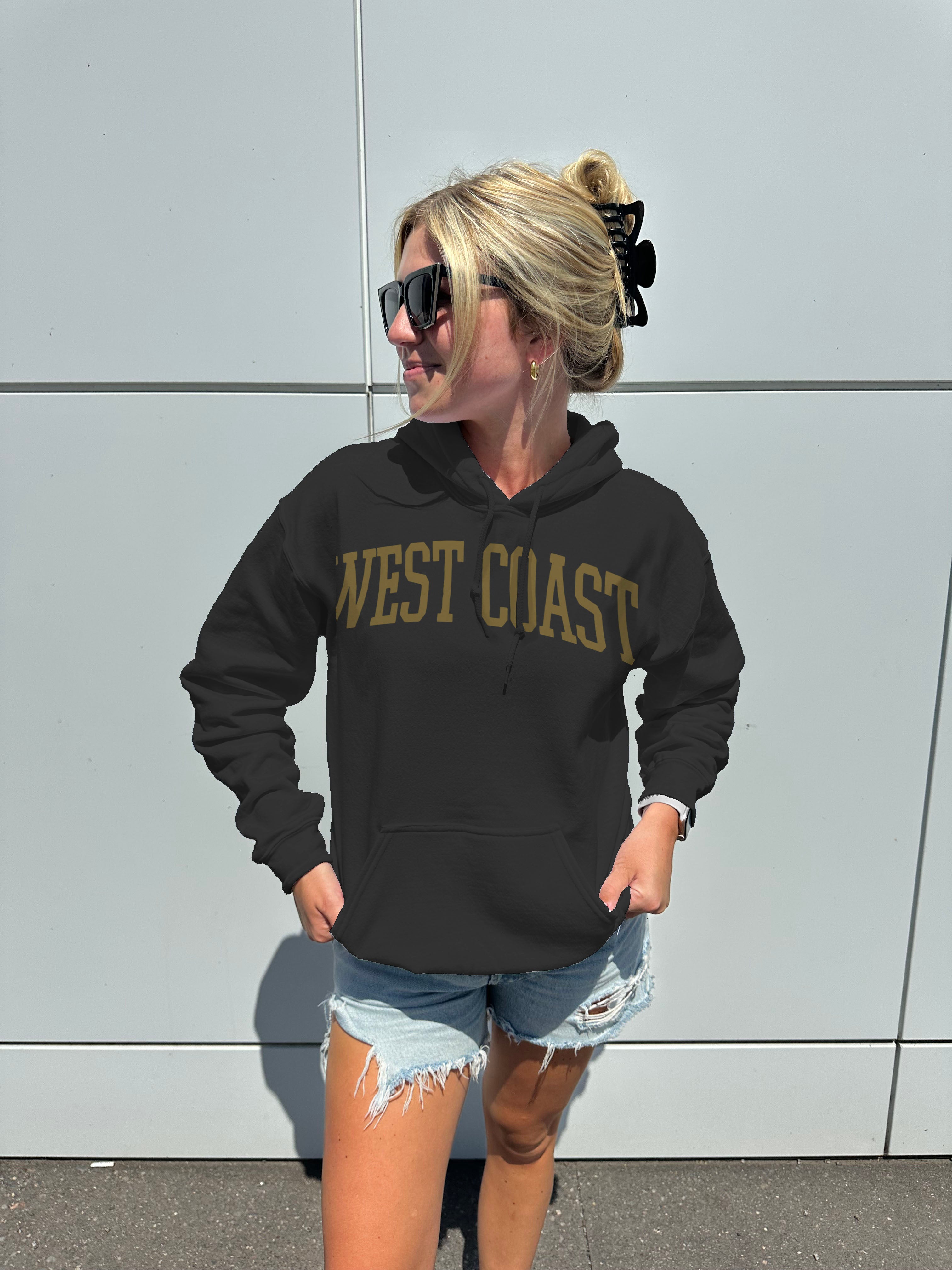 woman in black hoodie that says " West Coast" in golden text